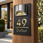 Plaque de maison acrylique solaire installée à côté de la porte