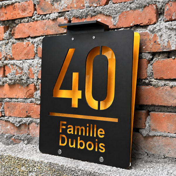 Plaque de maison solaire avec numéro et nom, sur un mur en briques